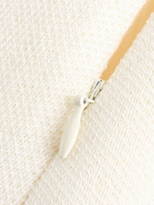 Close-up of cream knit fabric texture with matching invisible zipper on V-neck set
