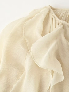 Detail van een ivoren chiffon blouse met gelaagde ruffles en verfijnde plissé afwerkingen