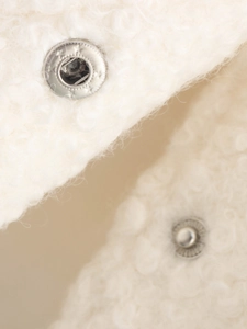 Gros plan sur la texture pelucheuse blanche et le bouton-pression en métal argenté