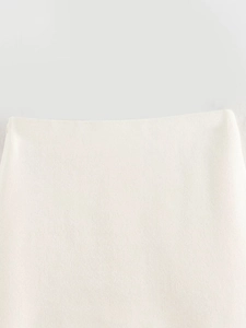 Close-up detail of cream knit skirt waistline showing fabric texture and seamless finish