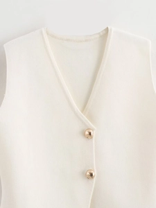 Detailed close-up of cream knit vest featuring elegant V-neck and golden metal buttons