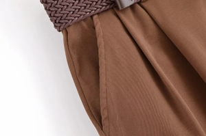 Détail d'un short marron foncé avec poches latérales et une ceinture tressée marron foncé