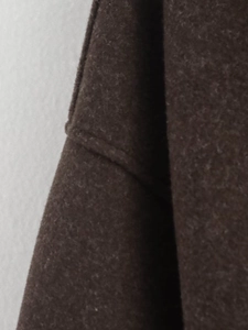 Dettaglio della cucitura e della consistenza del cappotto in lana marrone scuro