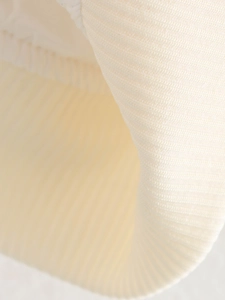Détail du blouson aviateur en maille crème montrant la texture côtelée et la matière fine