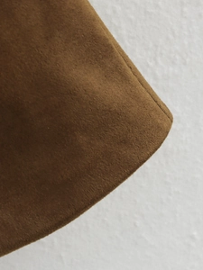 Detailed close-up of brown suede fabric showing fine texture and precision stitching