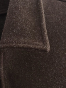 Dettaglio macro del colletto del cappotto di lana marrone scuro con cuciture e trama