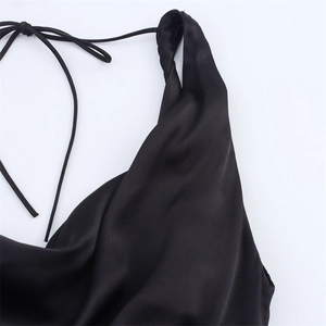 Détail d'une robe en satin noir avec col bénitier et fines lanières de fermeture au dos