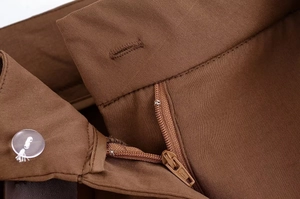 Détail de la taille du short marron montrant le bouton, le zip et la texture du tissu