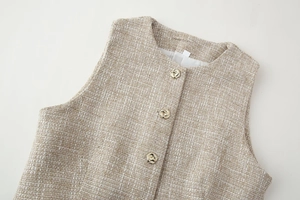 Dettaglio gilet in tweed con scollo rotondo e bottoni dorati in metallo a nodo