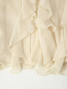 Detailweergave van crème ruches shirt met fijne plooien en delicate stoftextuur