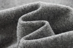Close-up of premium gray wool blend fabric showing thick texture and soft fiber details