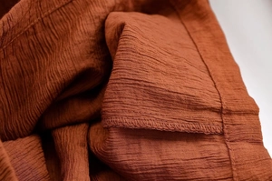 Detail von rostrot gekräuseltem Stoff mit hochwertiger Overlock-Naht-Verarbeitung