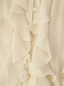 Detailopname van crème ruches blouse met V-hals, gelaagde textuur en witte ronde knopen