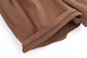 Gros plan sur l'ourlet roulé et les coutures de qualité du short tissé marron