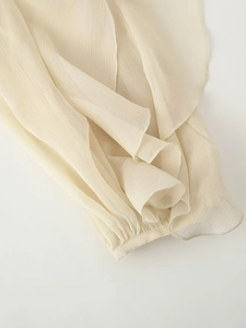 Detailopname van beige chiffon mouw met verticale textuur en ruches aan de manchetten