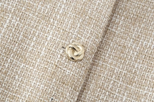 Dettaglio del tessuto tweed con bottone in metallo dorato dal design a nodo a spirale