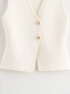 Detail shot of white knitted vest showing texture and large golden ball buttons