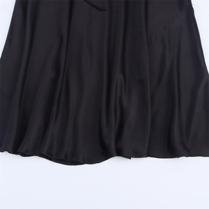 Détail montrant la texture brillante et le drapé fluide d'un tissu en satin noir