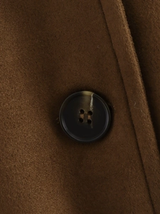 Macro shot of warm brown suede fabric with a textured resin four-hole button detail