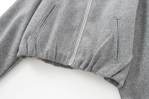 Detail of grey wool bomber jacket featuring metal zipper and ribbed elastic hemline