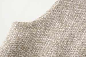 Dettaglio della trama del tessuto in tweed beige con fibbia in metallo e dettagli intrecciati