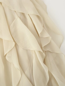 Detailopname van meerlaagse ruches op een crèmekleurige chiffon blouse met fijne afwerking
