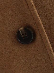 Detailed close-up of brown suede fabric with a marble texture button and fine stitching