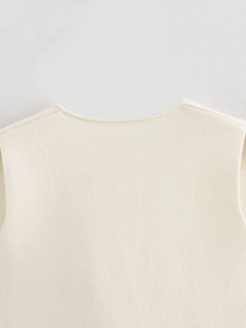 Close-up of the cream knit vest neckline showing refined stitching and soft fabric texture