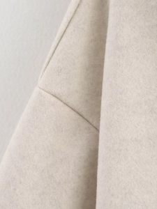 Dettaglio del tessuto beige del cappotto di lana con cuciture e trama di qualità