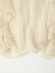 Macro-opname van de crème gelaagde ruches en de verticale textuur van de chiffon blouse