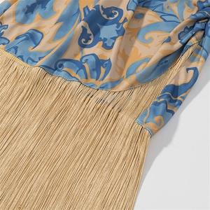 Dettaglio vestito boho con rifiniture in frange dorate e stampa floreale blu vintage