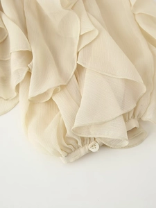 Detailweergave van de crèmekleurige chiffon blouse met gelaagde ruches en geplooide manchetten
