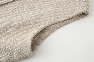 Dettaglio macro della trama del tessuto in tweed beige e cuciture di un gilet
