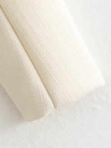 Macro del tessuto tweed crema che mostra la trama fine e i dettagli della cucitura