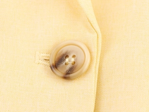Detailed macro of a marbled four-hole button on high-quality yellow woven fabric