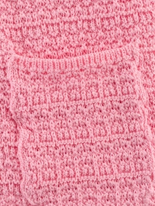 Gros plan sur la maille gaufrée rose montrant les détails du tissu tricoté doux