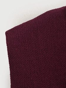 Gros plan du tissu en maille jersey bordeaux montrant les détails de couture et texture