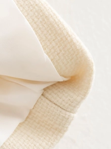Dettaglio della trama del tessuto tweed crema con morbida fodera interna bianca
