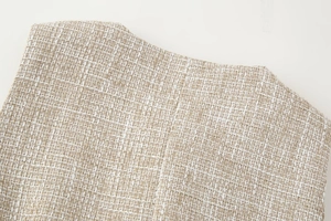 Dettaglio ravvicinato del tessuto tweed beige con trama intrecciata e motivi raffinati
