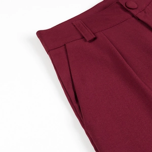 Detailed macro view of wine red suit pants featuring a button waist, belt loops and pockets