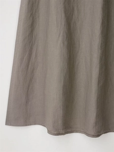 Gros plan détaillé de l'ourlet de jupe en lin taupe montrant la texture du tissu et couture