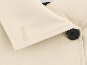 Detail shot of khaki trench coat collar with premium twill texture and black button