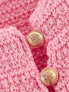 Gros plan détaillé du cardigan en tricot rose avec tissu texturé et boutons dorés