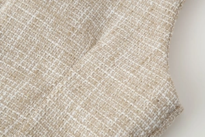 Macro primo piano del tessuto tweed beige e crema che mostra dettagli della trama intrecciata