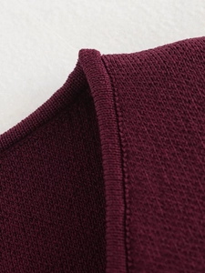 Gros plan sur le gilet en tricot rouge vin montrant les coutures et la texture du tissu