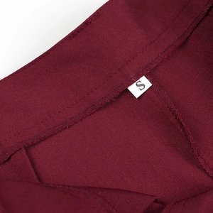 Detailed macro shot of deep red twill fabric stitching and size S garment tag