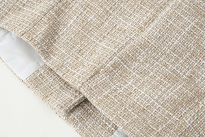 Vista dettagliata del tessuto tweed beige con fodera interna liscia e bordi ben rifiniti