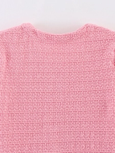 Gros plan du col rond d'un pull en maille gaufrée rose montrant les détails du tissage