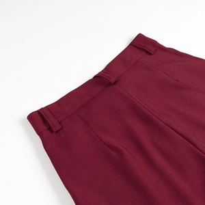 Detailed macro view of the belt loops and stitched waistband on burgundy trousers