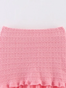 Gros plan sur la maille gaufrée rose et les bords volantés des vêtements en maille